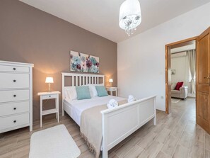 A bedroom with a bed, bedside tables, a dresser, a chandelier, and a painting on the wall. - Vacation home  by Interhome (Pridraga)
