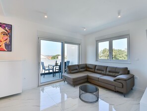 A spacious living area with a large sectional sofa, a dining table with chairs, and a sliding glass door leading to an outdoor patio. - Apartment  by Interhome (Zadar/Bibinje)