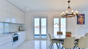 Eine moderne Küche mit weißen Schränken, einem eingebauten Ofen und einem Essbereich mit Tisch und Stühlen.