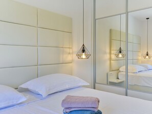 A hotel room with a large bed, white bedding, a headboard, and a mirror reflecting the room. - Apartment  by Interhome (Zadar/Bibinje)