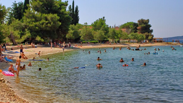 Ein Strand mit badenden und sonnenbadenden Personen.