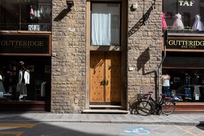 Ein Schaufenster mit Holztür, einem Fahrrad und Kleidermanniketten.
