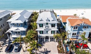A beachfront property with multiple buildings, a paved driveway, and parked cars. - Sea Swept | Luxury Beachfront Estate (Bradenton Beach)