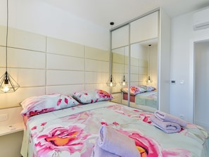 Ein Schlafzimmer mit einem Bett, einem großen Spiegel und einem Kleiderschrank.