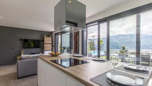 Eine moderne Küche mit einer großen Kochinsel, einem eingebauten Backofen und Bergblick durch große Fenster.