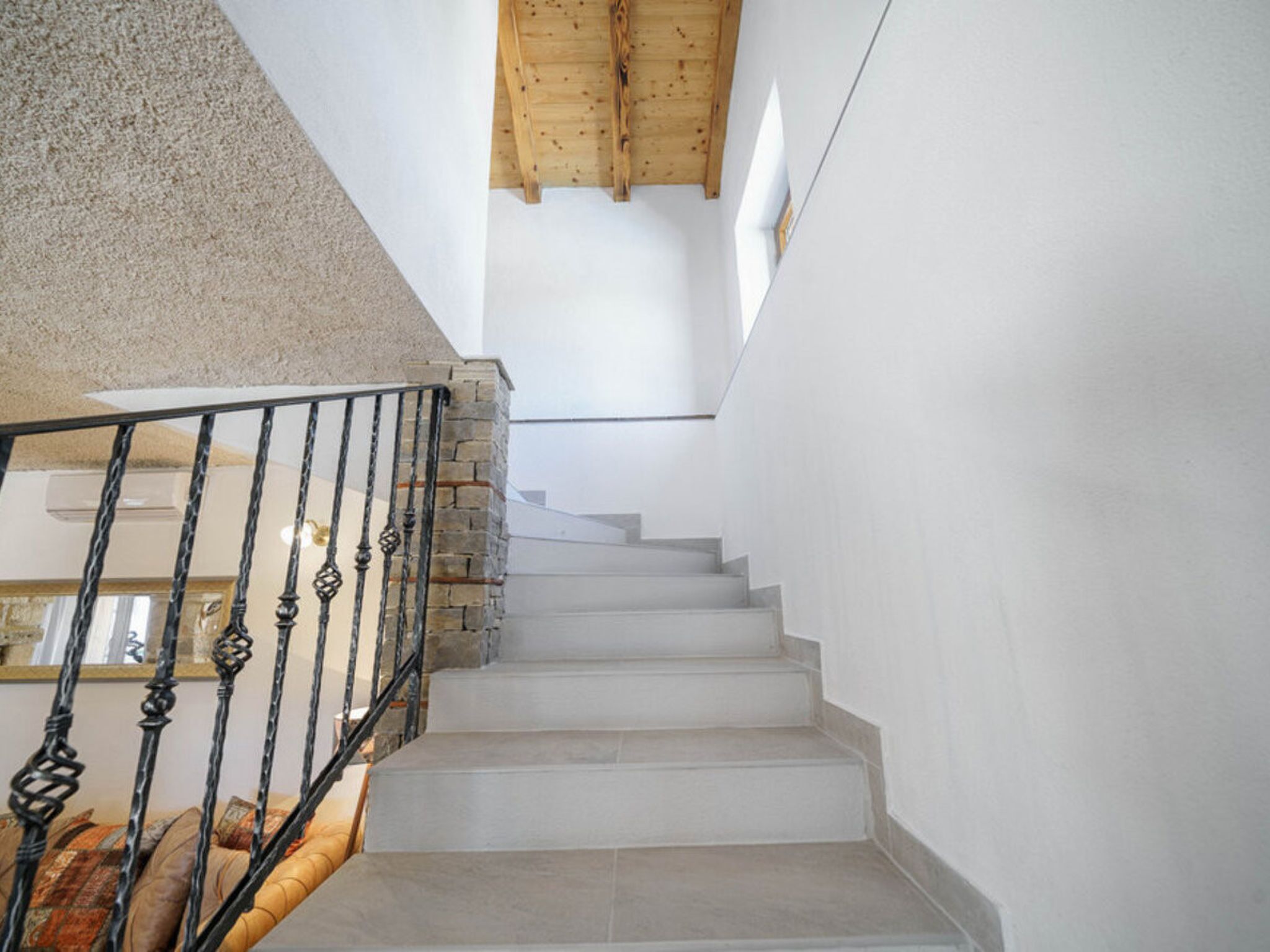 A staircase with a stone wall on one side and a wooden ceiling on the other.