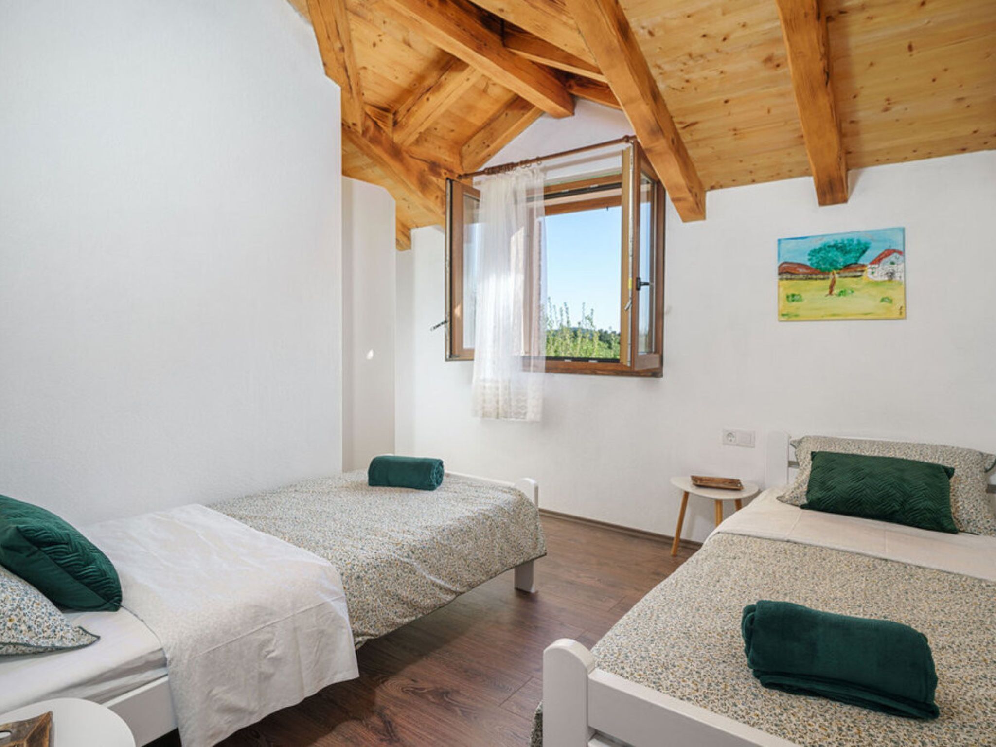 Una habitación con dos camas individuales, una mesita y un ventanal con cortinas.