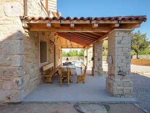 A stone building with a wooden pergola, a table, and benches. - Holiday Home Marilu with pool by Interhome (Budak)