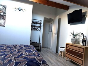 A bedroom with a bed, a dresser, a TV, a door, and a hallway. - Self-contained gîte for 2 people, with kitchen, close to the greenways. (PLAN D ORGON)