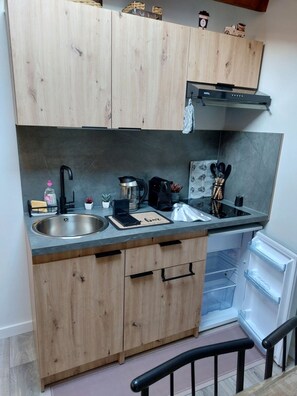 A compact kitchen with wooden cabinets, a stainless steel sink, a coffee maker, and a small refrigerator. - Self-contained gîte for 2 people, with kitchen, close to the greenways. (PLAN D ORGON)