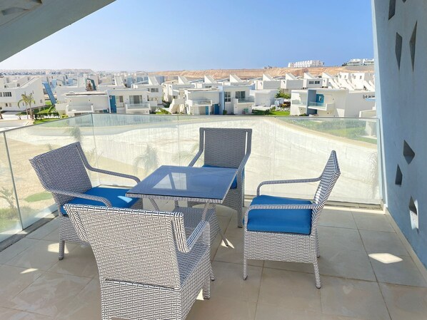 A balcony with wicker furniture and a clear view of the surrounding buildings. - Fouka North Coast CL4-CH13-03 (Marsa Matrouh)