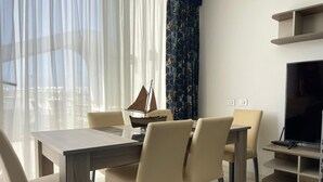 Ein moderner Essbereich mit einem Holztisch und Stühlen, einem kleinen Bootsmodell sowie einem Fernseher auf einem Schrank.