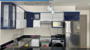 Eine moderne Küche mit schwarzem Arbeitsplatz, Edelstahlgeräten und blauen Schränken.