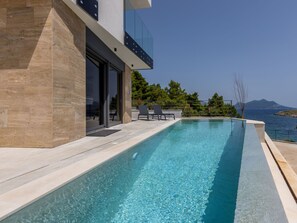 A modern pool with clear blue water, surrounded by a stone deck and a glass balustrade. - Beachfront villa Luce with seaview and pool by Interhome (Trstenik/Dingač)