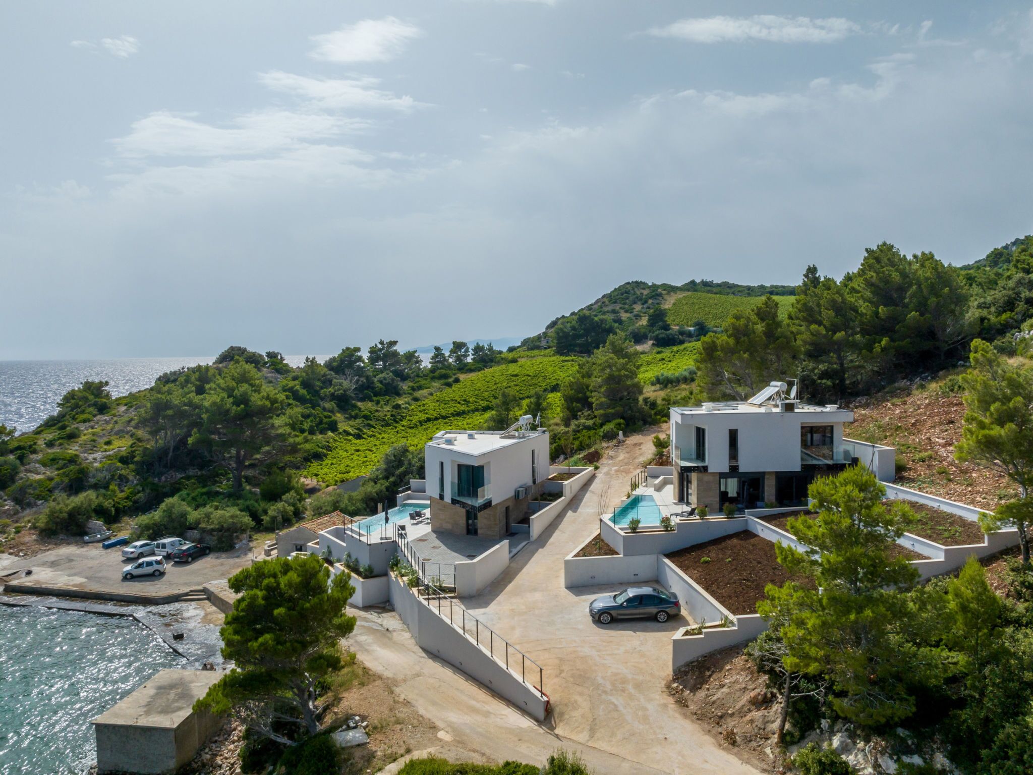 A coastal property with modern architecture, a swimming pool, and a view of the sea.