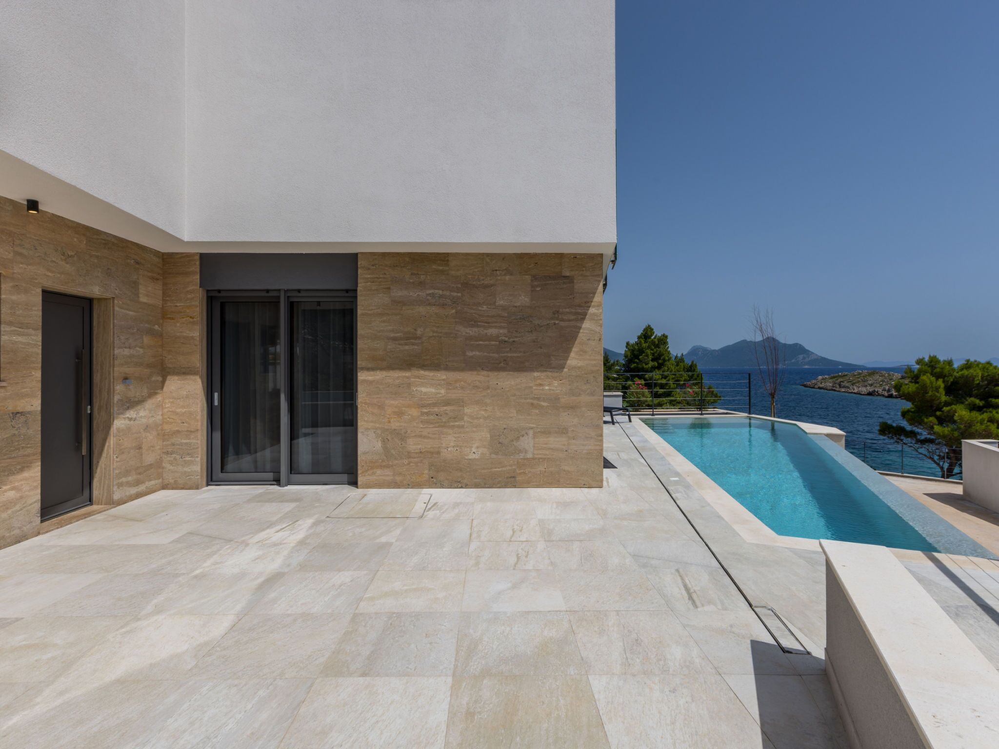 Ein modernes Gebäude mit Pool, einer Tür und Blick aufs Meer.