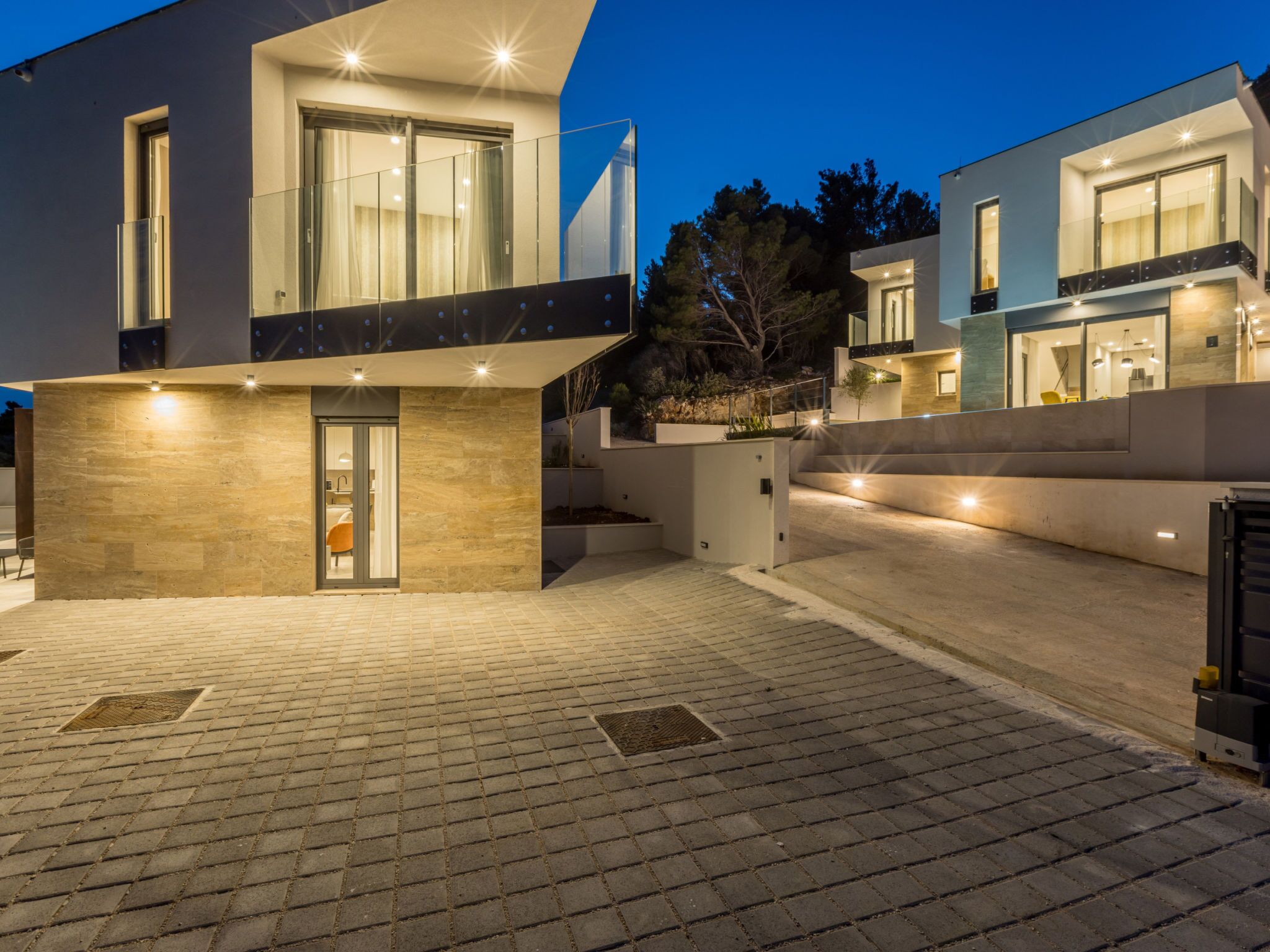 Una casa moderna de dos pisos con entrada visible y camino de entrada pavimentado.