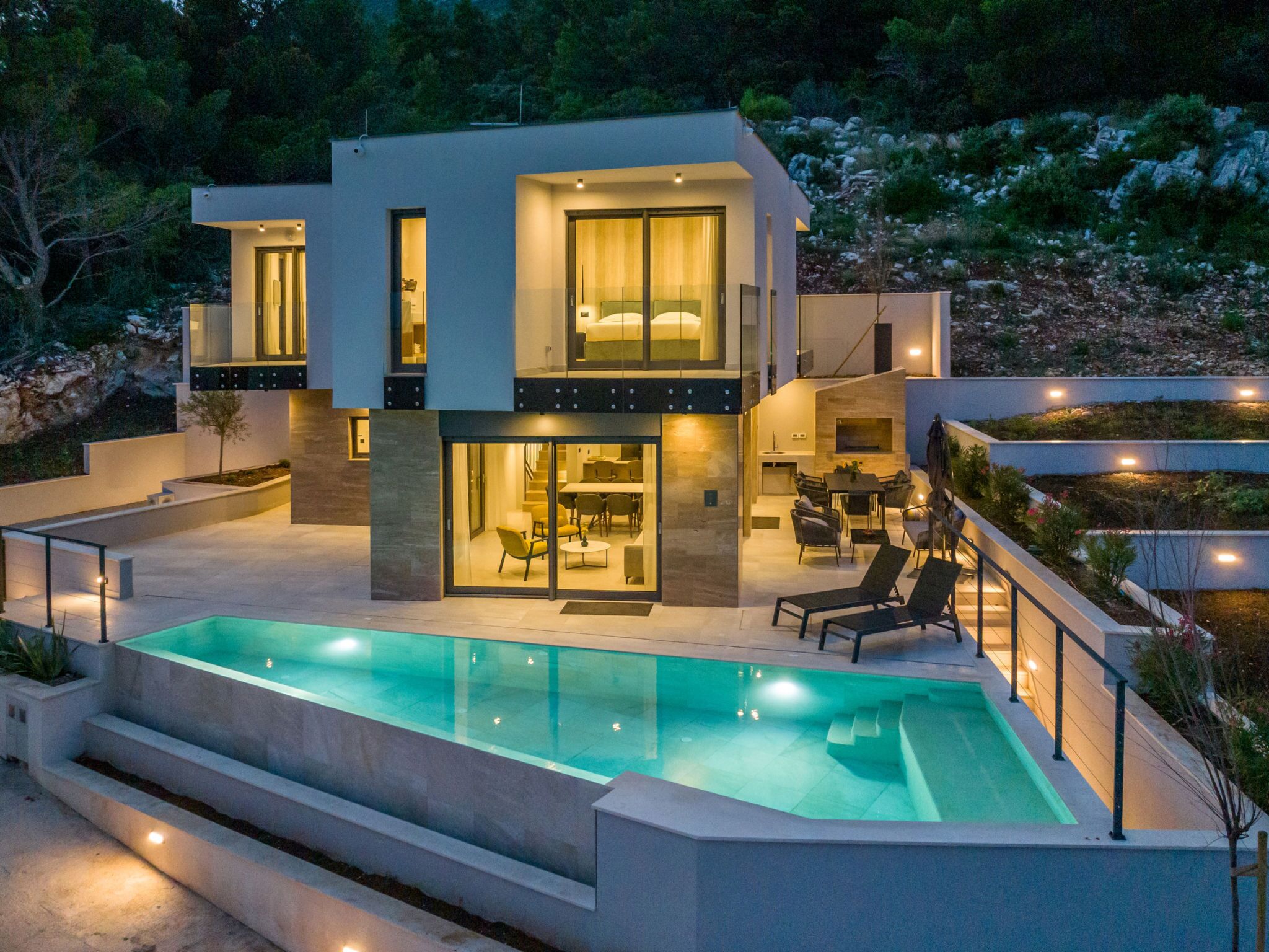 Une maison moderne à deux étages dotée d’une piscine, d’un espace extérieur aménagé et d’un coin repas.