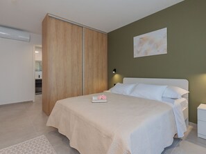 A bedroom with a bed, a wardrobe, a nightstand, and a wall-mounted light fixture. - Stunning Villa Marea with a private pool by Interhome (Vrsi)
