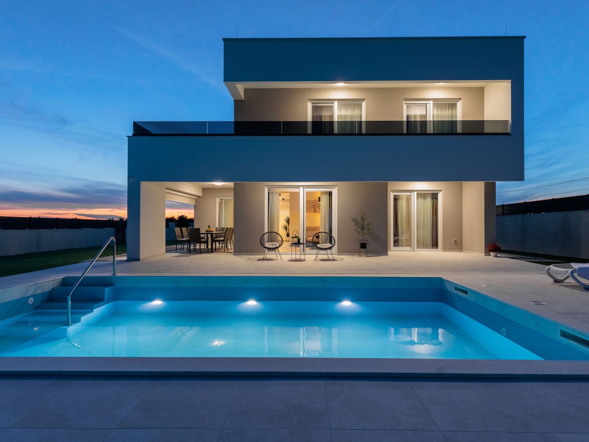 A modern two-story house with a swimming pool in the foreground.