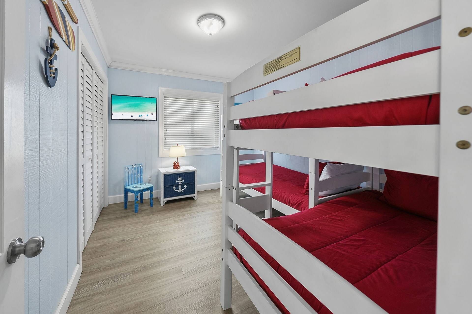 Een slaapkamer met stapelbed, raam, bureau en stoel.