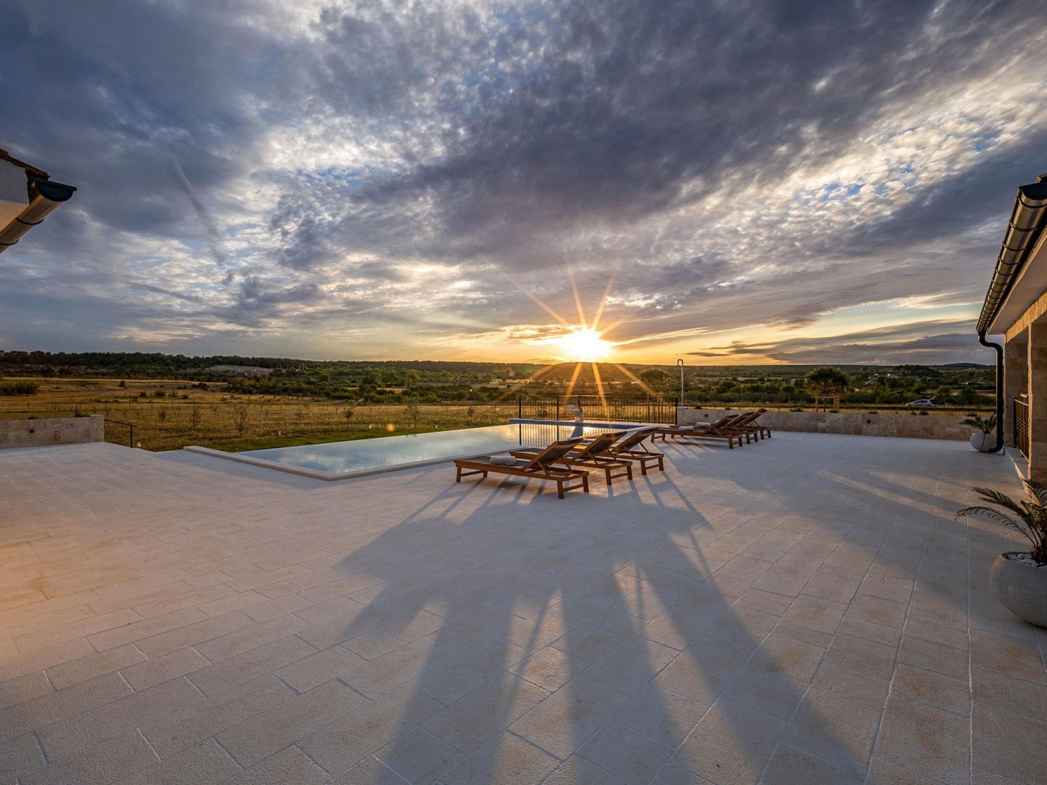 Zona de piscina en la azotea con tumbonas y vistas a la puesta de sol sobre el paisaje.