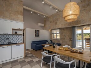 A modern kitchen with white cabinets, a blue sofa, and a dining area with a wooden table and chairs. - Charming villa Viliska with heated pool by Interhome (Donje Rastane)