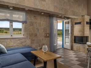 A room with stone walls, a sofa, a table, a TV, and a view of the outdoors. - Charming villa Viliska with heated pool by Interhome (Donje Rastane)