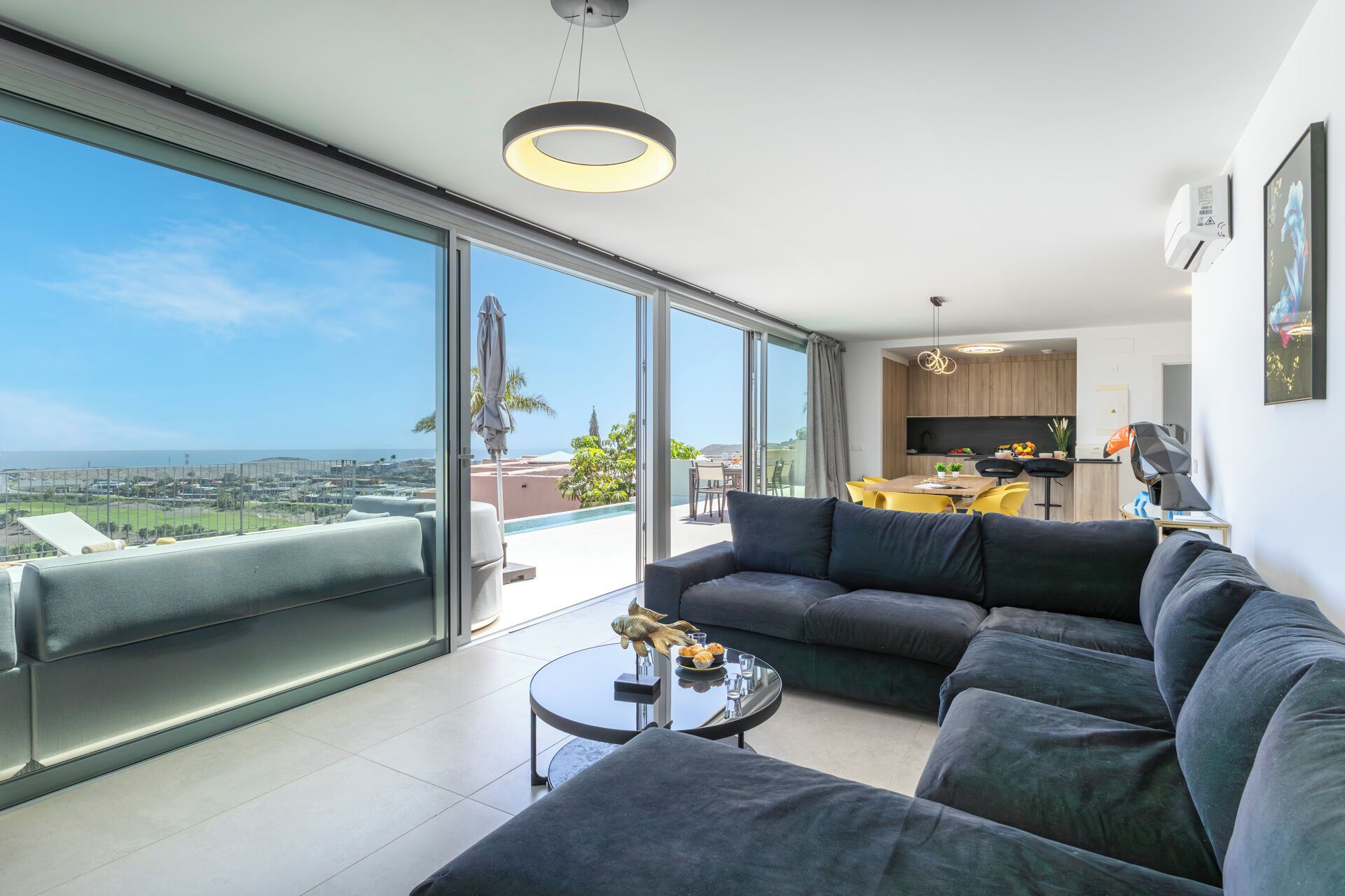 Un salon moderne avec un grand canapé, une table basse et une vue sur la ville et l’océan.