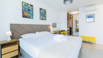 A modern hotel room with a large bed, bedside tables, a desk, and a wardrobe.
