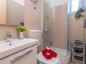 Une salle de bain équipée d’une douche, de toilettes, d’un lavabo et d’un porte-serviettes.