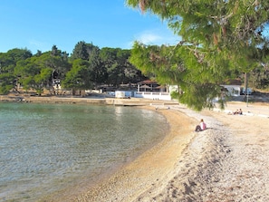 A beach with clear water, pebbles, and trees. There are people relaxing on the sand. - Holiday Home Ema with pool by Interhome (Biograd na Moru)
