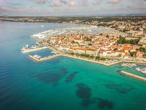 An aerial view of a coastal town with a marina, waterfront buildings, and a clear view of the sea. - Holiday Home Ema with pool by Interhome (Biograd na Moru)
