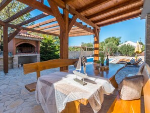 An outdoor patio with a brick oven, wooden pergola, and a swimming pool. - Holiday Home Ema with pool by Interhome (Biograd na Moru)