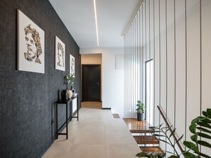 A modern hallway with a dark wall, a console table with a vase and books, and a staircase with a railing. - Villa Barbara with heated pool by Interhome (Drage)