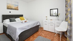 Ein modernes Schlafzimmer mit einem Bett, Nachttischen, einer Kommode, einem Sessel und einem Bild an der Wand.