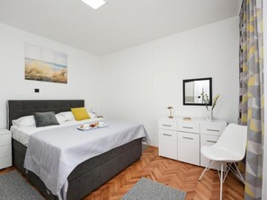 A modern bedroom with a bed, bedside tables, a dresser, a chair, and a painting on the wall. - Villa Mare with heated pool and gym by Interhome (Crno)