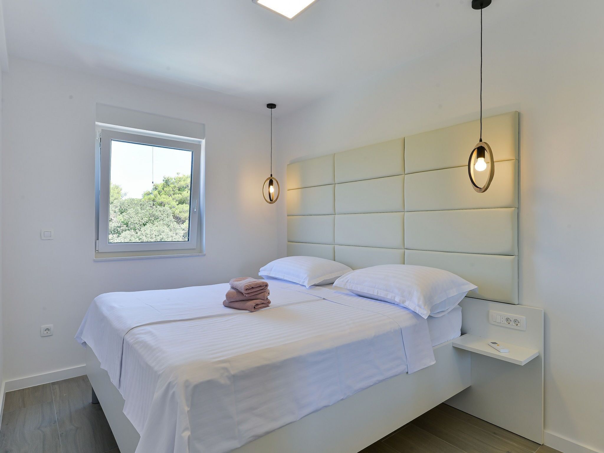 Une chambre à coucher comprenant un lit, une table de chevet, une fenêtre et un luminaire fixé au mur.