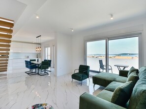 Un espace de vie moderne comprenant un coin repas, un canapé et une vue sur la mer.