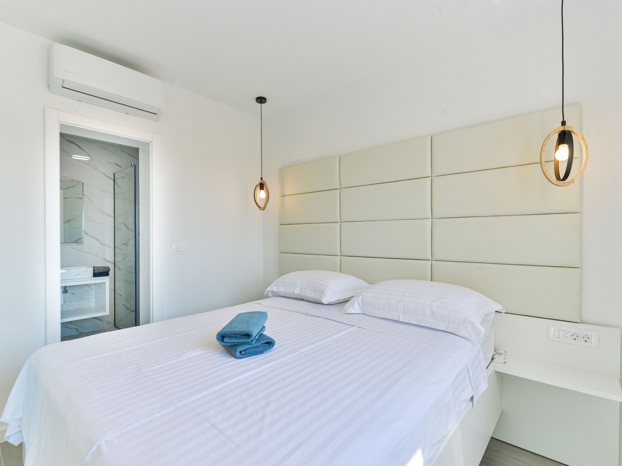 Une chambre d’hôtel comprenant un lit, une table de chevet, un miroir et une armoire intégrée.