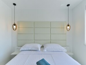 Une chambre d’hôtel avec un lit, deux tables de chevet et une tête de lit.