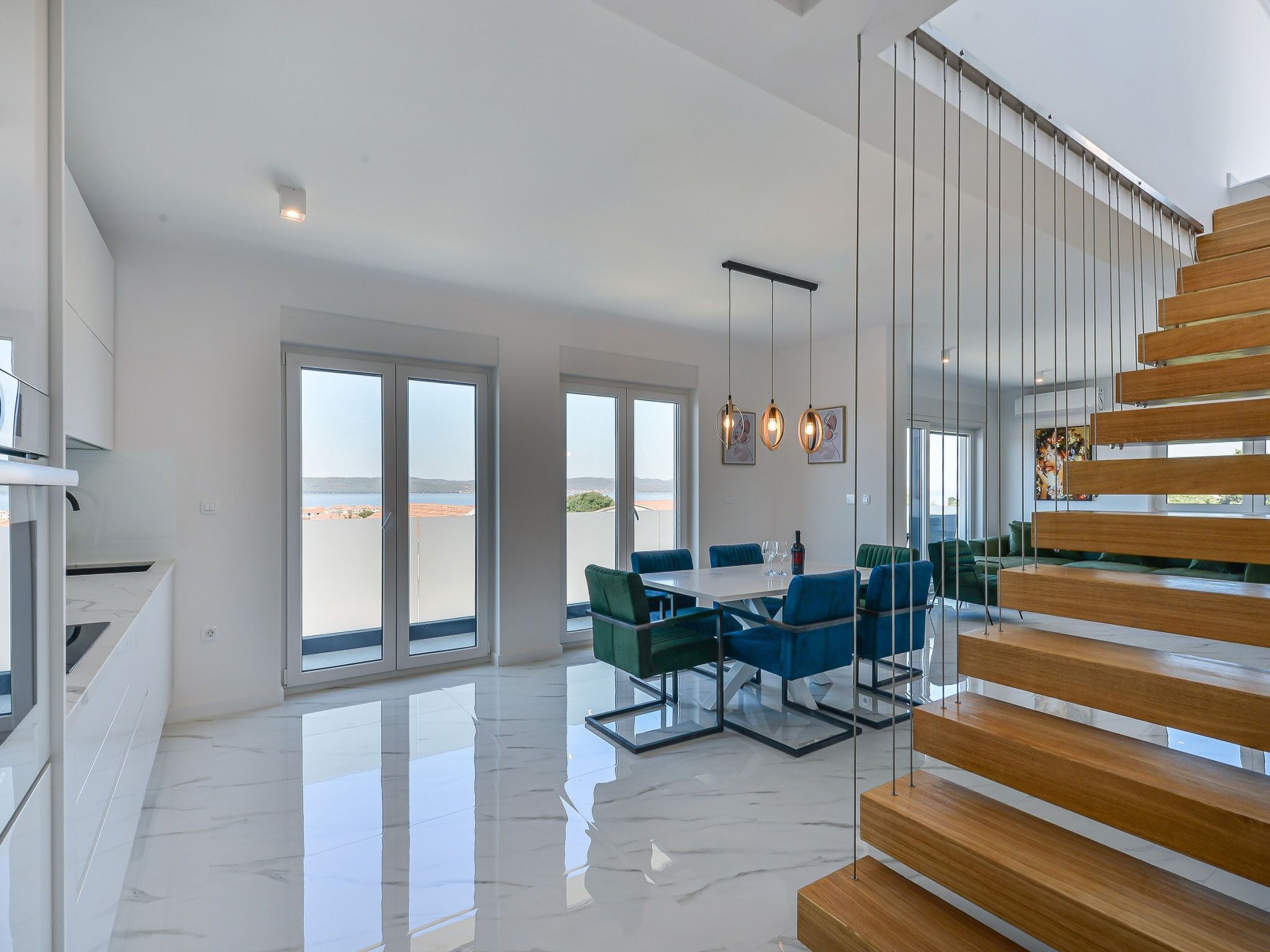 Un espacio habitable amplio con una escalera moderna, ventanas grandes y un juego de comedor.