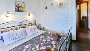 Ein Schlafzimmer mit einem Bett, einer Wandleuchte und einer Tür zu einem anderen Raum.