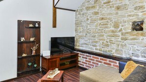 Ein gemütliches Wohnzimmer mit Steinwand, Flachbildfernseher, Holzmöbeln und Kamin aus Ziegelsteinen.