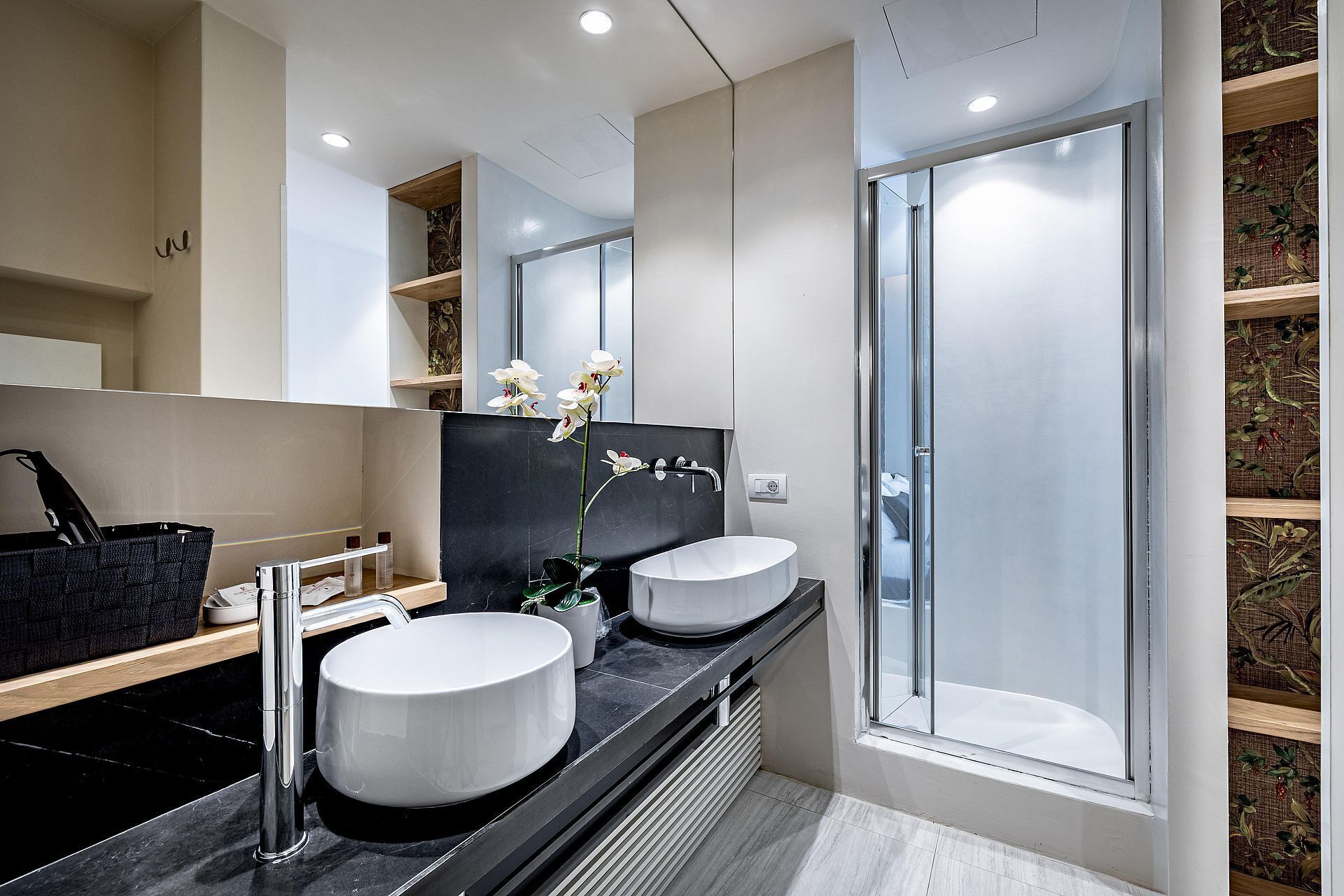 A modern bathroom with two sinks, a large mirror, and a shower.