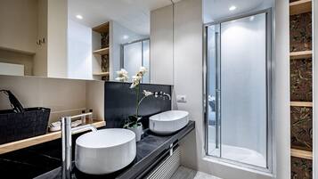 A modern bathroom with two sinks, a large mirror, and a shower.