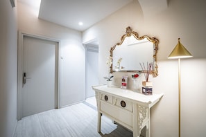 A bathroom with a white vanity, a mirror with an ornate frame, a gold lamp, and a potted plant. - Signoria Collection (Florence)