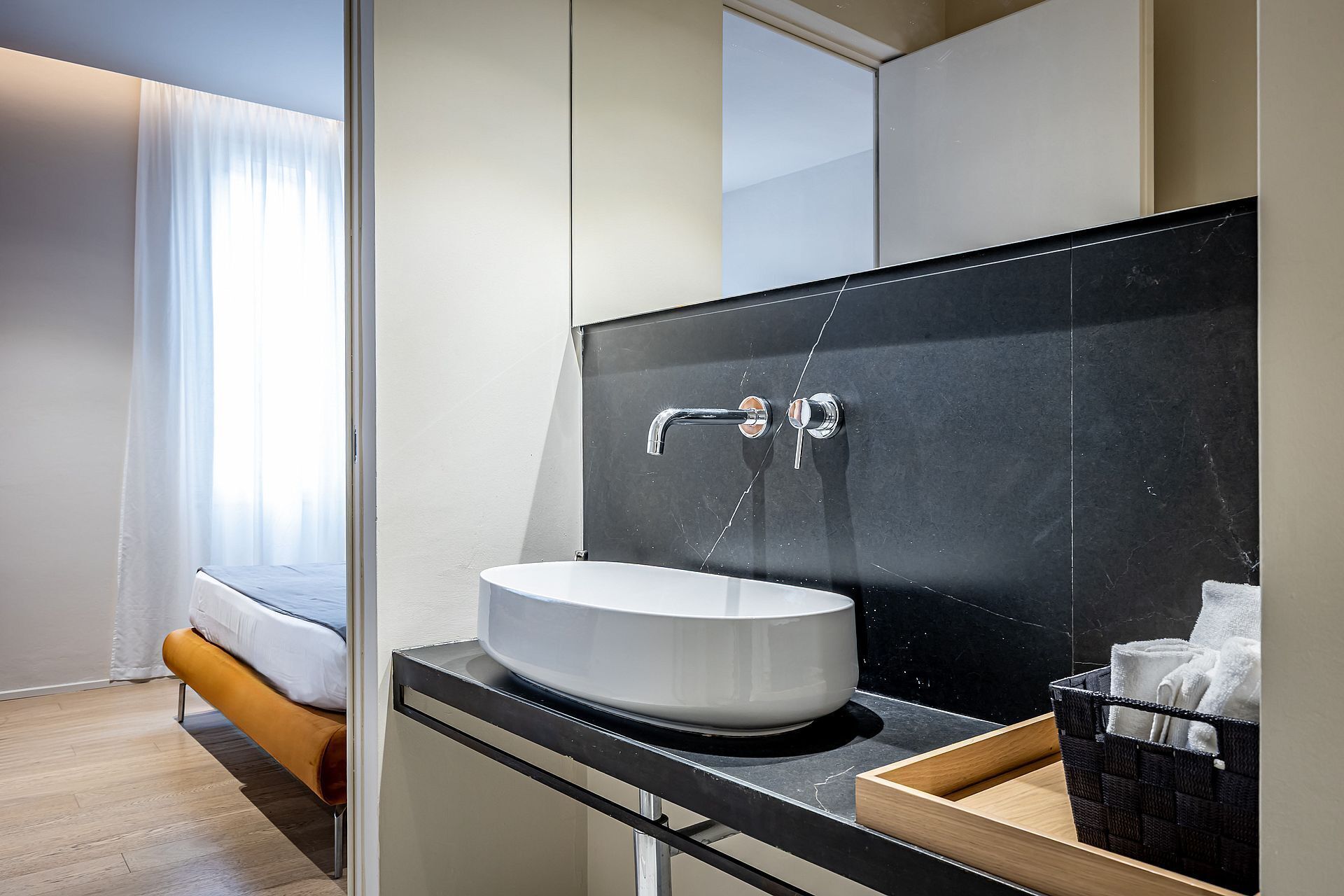 A modern bathroom with a white sink, black countertop, and a large mirror.