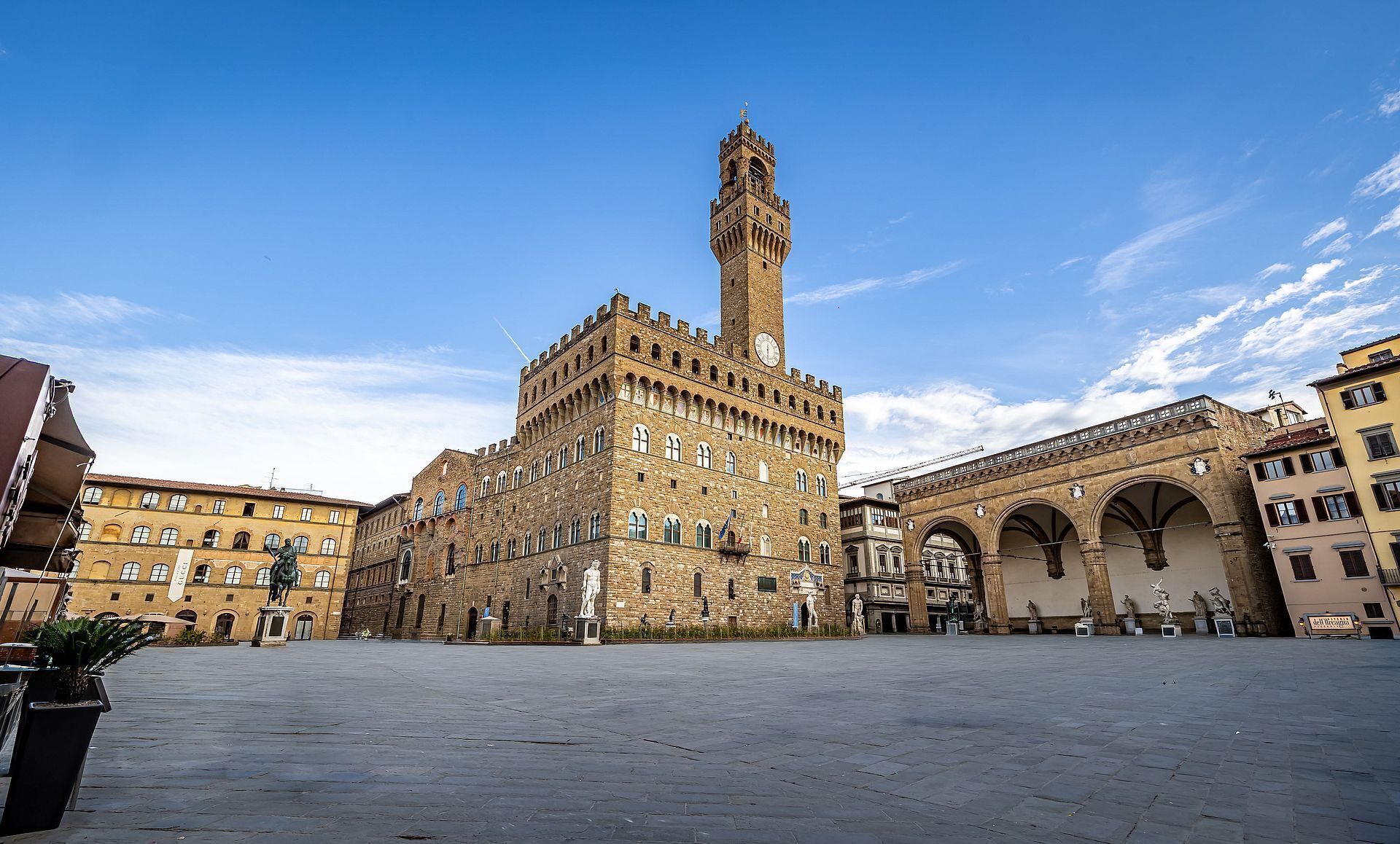 A historic building with a prominent tower, a large open plaza, and classical architecture.