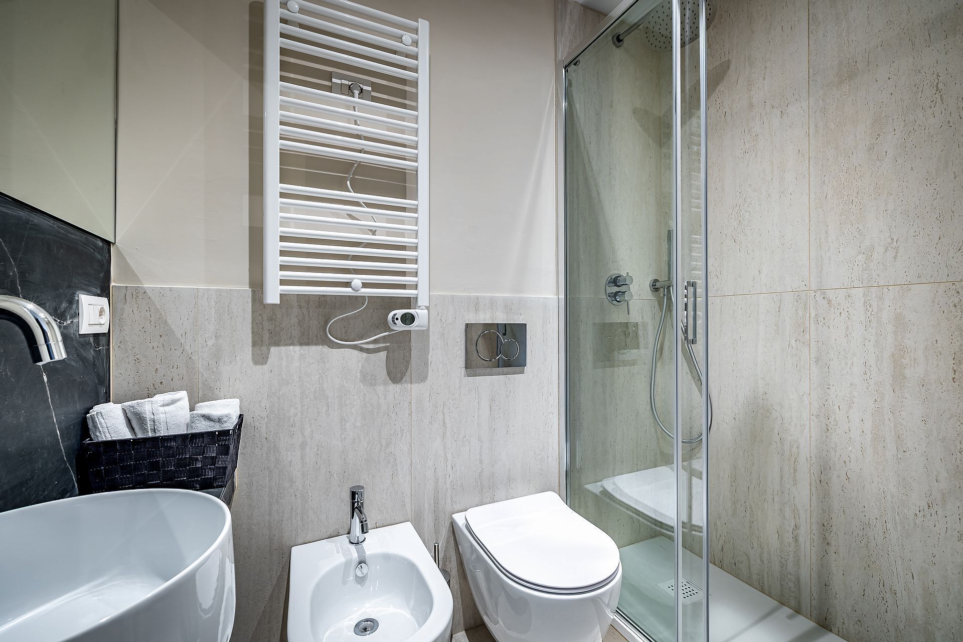 A modern bathroom with a bathtub, a sink, a toilet, and a glass-enclosed shower.